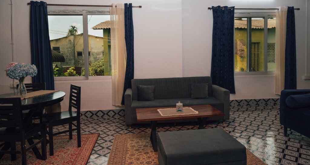 Sofa with two windows, dining table, and a small table.