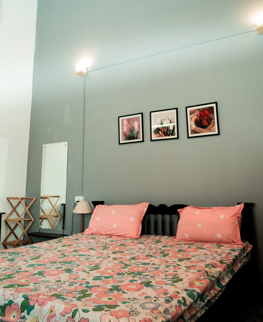 Double bed with a wall painting, bedside lamp, and mirror
