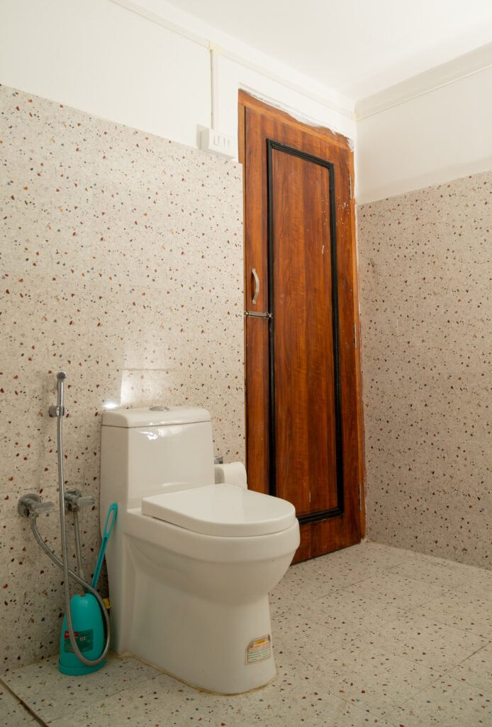Bathroom with commode, gate, tiled walls, and a Muslim shower