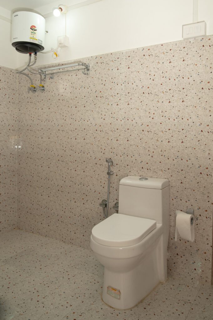 Bathroom with commode, toilet paper, and wall-mounted hanger rack