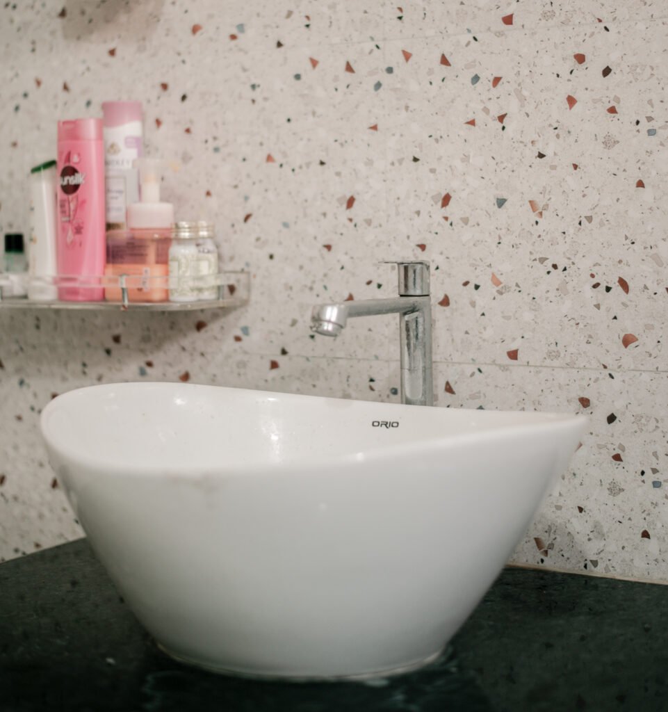 Modern bathroom sink with faucet and shelf holding toiletries