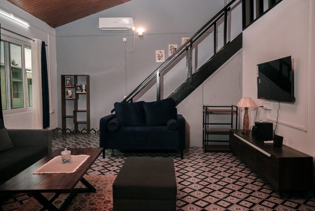 Spacious lounge area featuring sofa, TV, stairs, and warm lighting